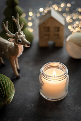 Eine brennende Kerze umrahmt von moderner Weihnachtsdekrotation. Nahaufnahme.