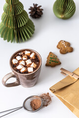 Eine heiße Schokolade mit Marshmellows, Lebkuchen Kekse und eine Geschenk Tüte auf einem weißen Tisch. Weihnachten.