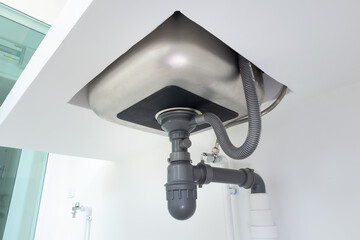 Drain pipe or sewer under kitchen sink. Pvc plastic pipe and
 flexible supply tube connection to...