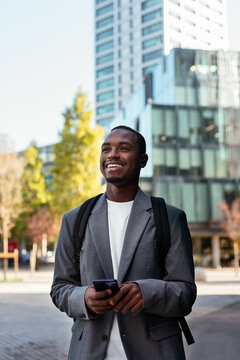Positive black executive man browsing smartphone