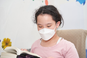 asia young girl wear protect mask for covid-19 reading book in home