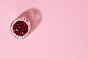 Krill oil pills on a pastel pink background with copy space