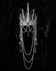 beautiful silver crown with pearl pendants on a black shiny background, accessory headdress, close-up