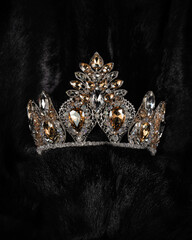 beautiful silver crown with a yellow stone for a beauty pageant on a black background, accessory...