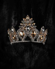 beautiful silver crown with a yellow stone for a beauty pageant on a black background, accessory headdress, close-up © mira_y