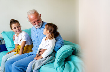 Obraz premium Happy grandfather and his grandchildren laughing and enjoying leisure time together.