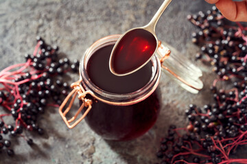 A spoon with black elder syrup made from fresh elderberries - obrazy, fototapety, plakaty