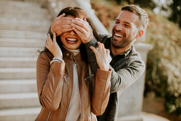 Fototapeta premium Young man covering the eyes of his girlfiend in the park
