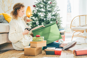 Woman wrapping Christmas gifts at home. Packing of the Christmas presents.