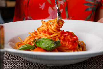 Spaghetti con sugo di pomodoro e basilico mentre vengono arrotolati con la forchetta