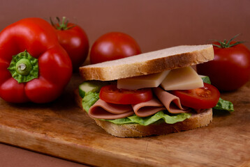 Sandwich toast bread with ham, cheese and vegetables stock images. Healthy sandwich with tomatoes and peppers on a wooden board still life stock photo
