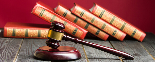 Law concept - Open law book with a wooden judges gavel on table in a courtroom or law enforcement...
