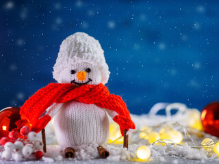 Obraz premium Happy Christmas snowman on skis made of cinnamon sticks. Festive decoration, fake snow, garland and blue background with copy space