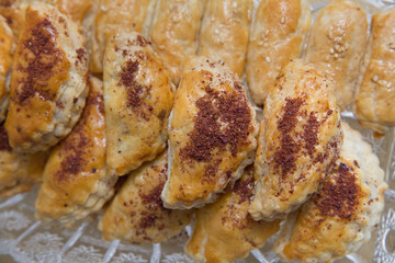 Baked pies in the oven. On a white plate and a peach color background . Pies with meat, cabbage or any filling.