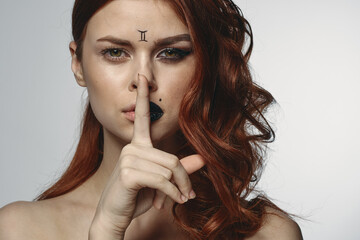 Naklejka premium pretty woman with zodiac sign on her face red hair close-up