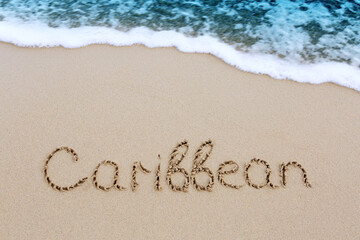 Word Caribbean written on the sand near the sea.