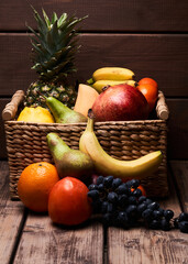 Mix of fresh juicy colorful exotic tropical fruits in basket on wooden background