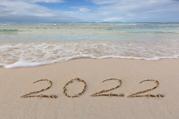 New Year 2022 written at the caribbean sand beach with sea wave .
