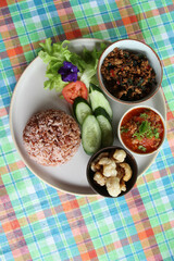 Thai style food, rice with stir fried basil with pork, chili paste, pork kappa and vegetable on white plate.