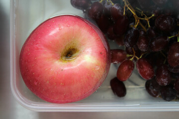The fresh apple and grape in the water to wash before eating.