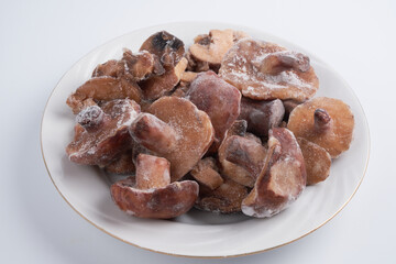 Frozen mushrooms close-up isolated on white plate, brown champignon prepared for cooking