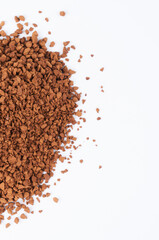 Freeze-dried instant coffee on white background close-up. Heap of powdered brown coffee product scattered on the table