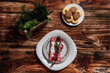 Christmas decor on a wooden table with cookies and a table place setting for dinner