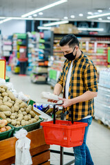 Young handsome man in a supermarket wearing protective mask while grocery shopping