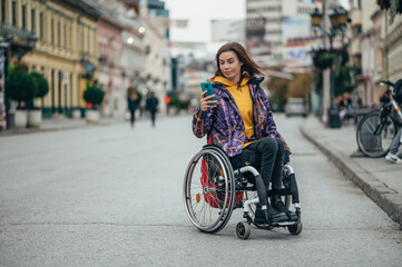 Obraz premium Woman in wheelchair using a smartphone while out in the city