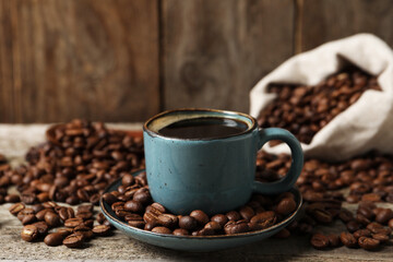 Cup of aromatic coffee and beans on wooden table