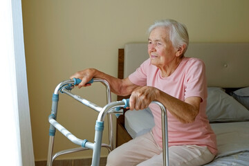 Elderly woman in nursing home room holding walking frame with wrinkled hand. Senior lady grabbing...