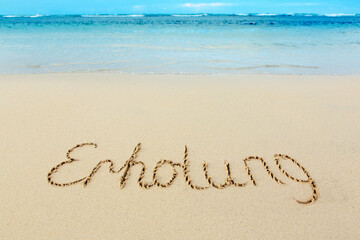 Word recreation written on the sand near the sea.