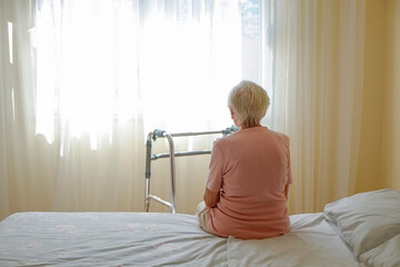 Elderly woman in nursing home room holding walking frame with wrinkled hand. Senior lady grabbing...