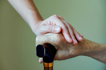 Senior woman holding quad cane handle in elderly care facility. Hospital nurse comforting mature...