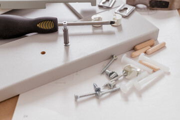 Furniture assembly services concept. Parts and tools for assembling furniture on the floor. Set of screws and screwdriver with nobody
