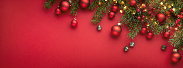 Red Christmas banner with fir branches, lights and decorations .