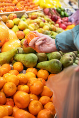 Hands of a woman choosing mandarine at fruit and vegetable market