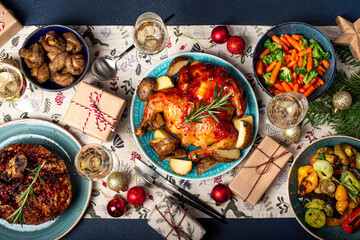 Christmas evening table top view with festive food and sparkling wine glasses, Xmas dinner with assorted delicious meals, wrapped presents and fir tree flat lay 
