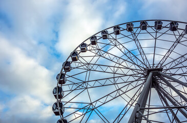 City park with a view of the Ferris Wheel attraction on a spring day, close-up.