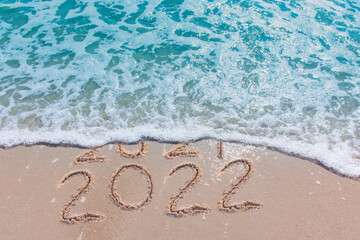 Message Year 2021 replaced by 2022 written on beach sand background. 
Good bye 2021 hello to 2022 happy New Year coming concept.
