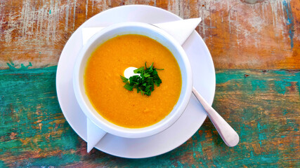 Delicious chickpea cream soup in ceramic cup on old fashioned table viewed from top.