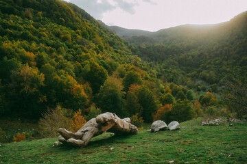 Piece of an old broken statue in a mountainous landscape with trees and greenery