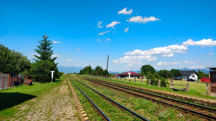 Fototapeta na wymiar Straight railway track going from the station into the horizon during beautiful Summer day in Slovakia.