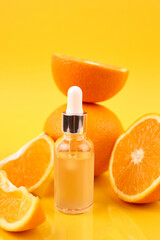 Pipette with orange essential oil over bottle and oranges on yellow background. Natural medicine concept. Aromatherapy