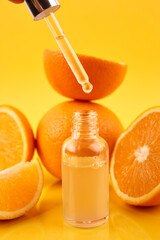 Pipette with orange essential oil over bottle and oranges on yellow background. Natural medicine concept. Aromatherapy