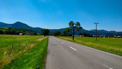 Fototapeta na wymiar Road in the countryside of Slovakia with mountains in the background going through agriculture are during beautiful Summer day.