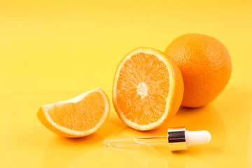 Pipette with orange essential oil over bottle and oranges on yellow background. Natural medicine concept. Aromatherapy