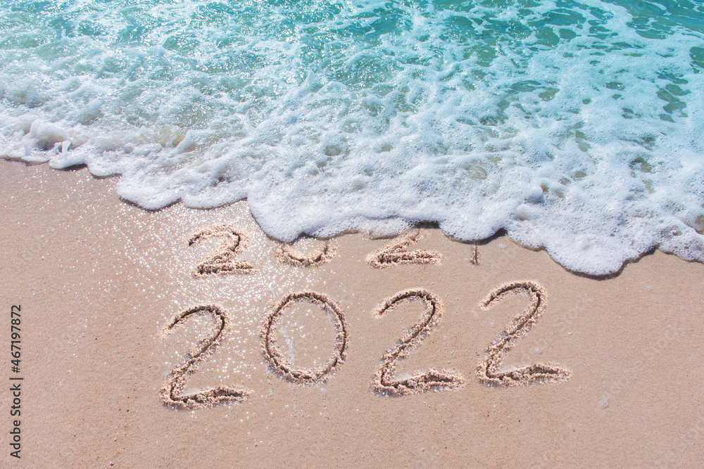 Wall mural message year 2021 replaced by 2022 written on beach sand background. good bye 2021 hello to 2022 hap