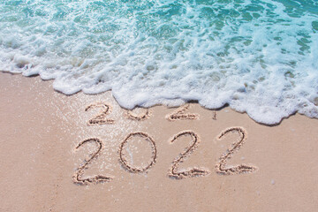Message Year 2021 replaced by 2022 written on beach sand background. 
Good bye 2021 hello to 2022...