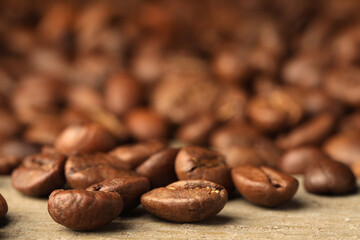 Many roasted coffee beans on wooden table, closeup